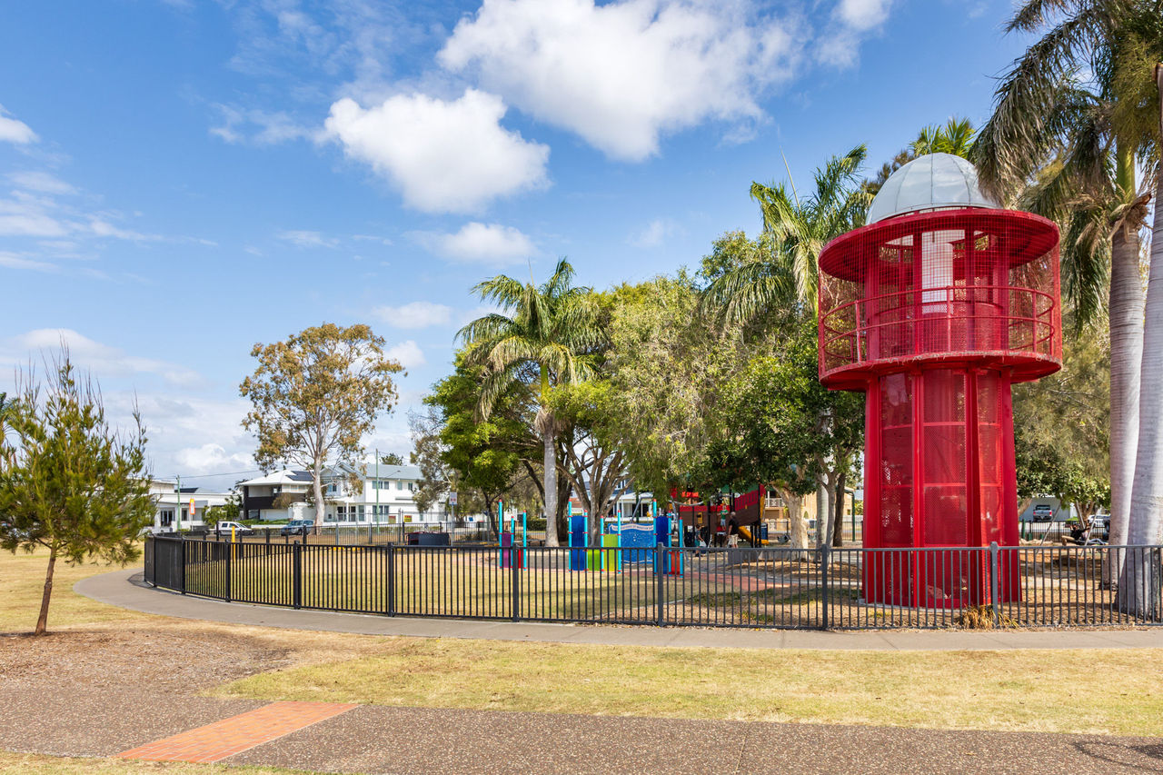 The fenced play area at George Clayton Park, featuring a lighthouse play tower and playground.