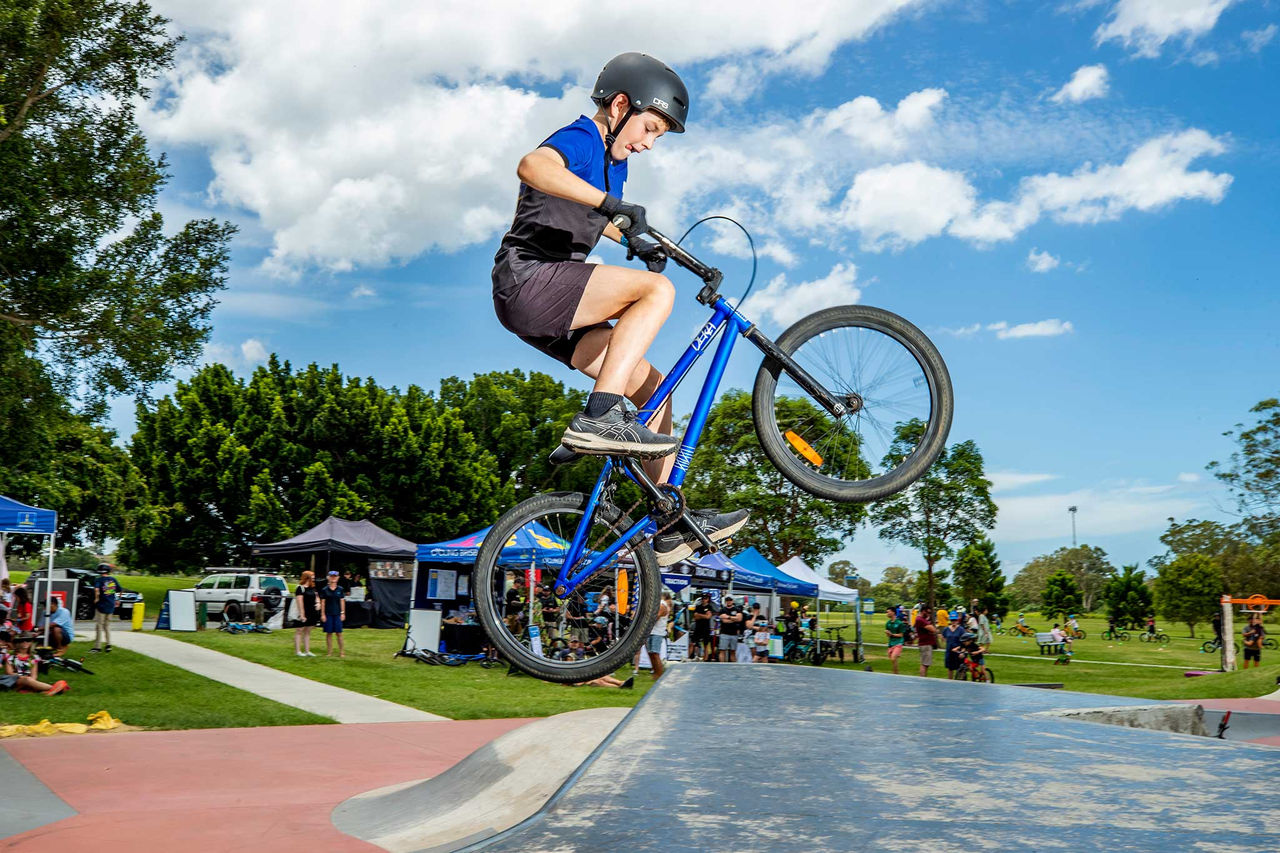 A child jumping a bike at an event in a park.