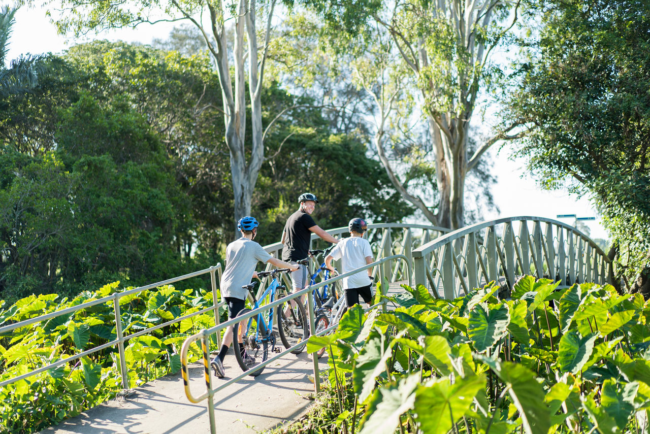 Dad and 2 sons pushing bikes over a shared bike/pedestrian bridge in Minnippi Parklands.