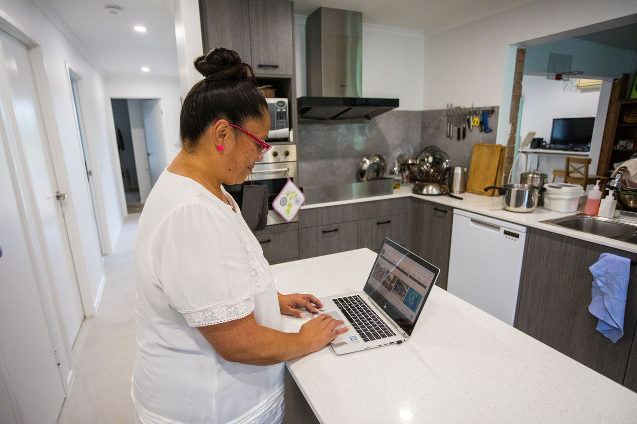 Woman standing at a counter using a laptop.