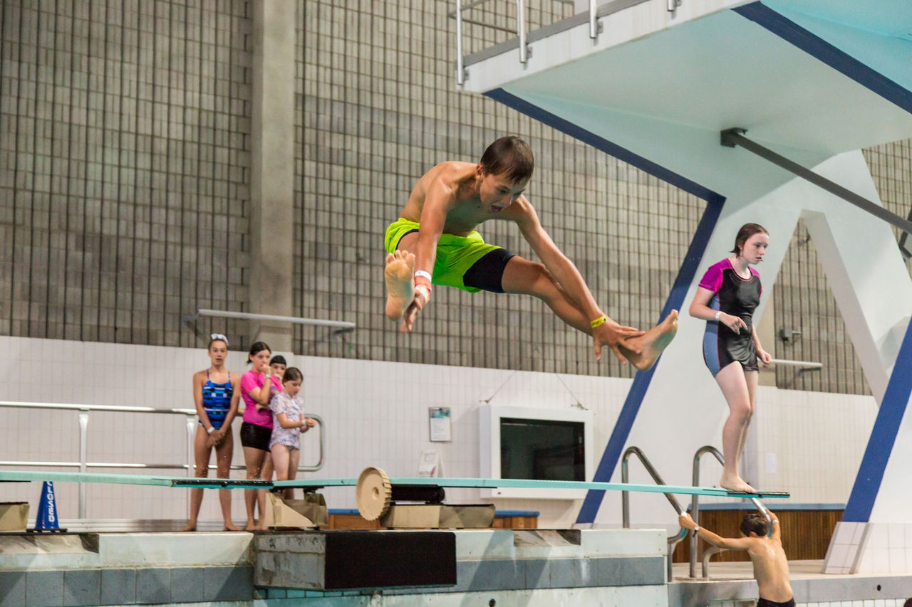 A child dives off a springboard into a pool.