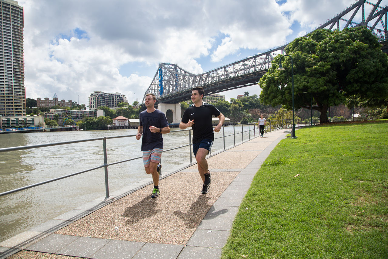 2 men running along the Brisbane River at Kangaroo Point. Story Bridge in background.