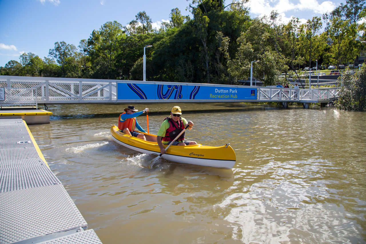 Two people kayak near a pontoon.