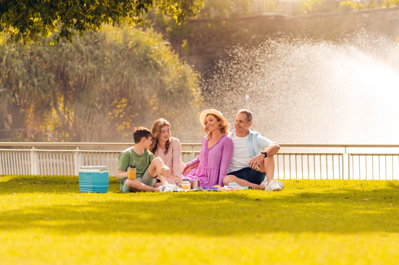 Family having a picnic on a rug at Roma Street Parkland.