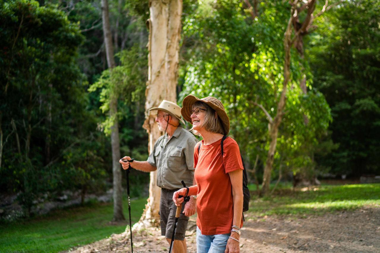 Mature couple walking  with walking poles at Mt Coot-tha Reserve.