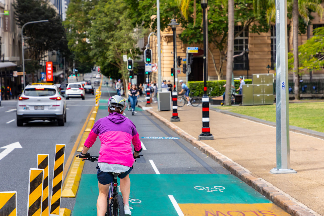 Cyclists in CityLink Cycleway and vehicles travelling past Queens Park on George Street, Brisbane City.