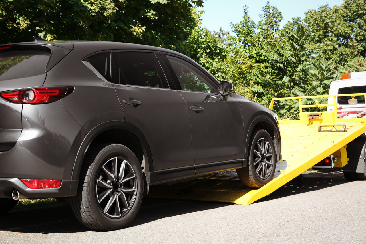 Grey SUV being loaded onto a yellow tray of a tow truck.
