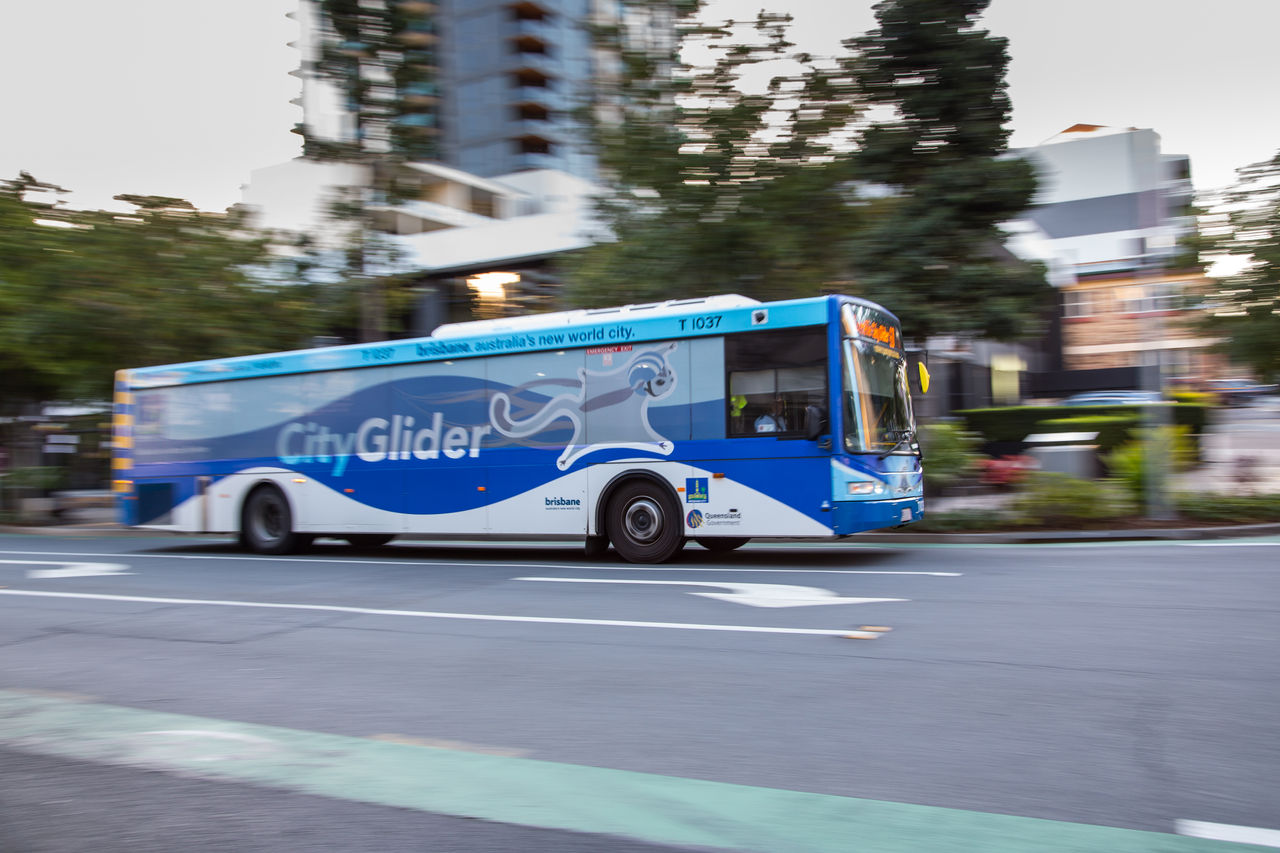 Blue-toned CityGlider bus driving along Melbourne Street, South Brisbane.