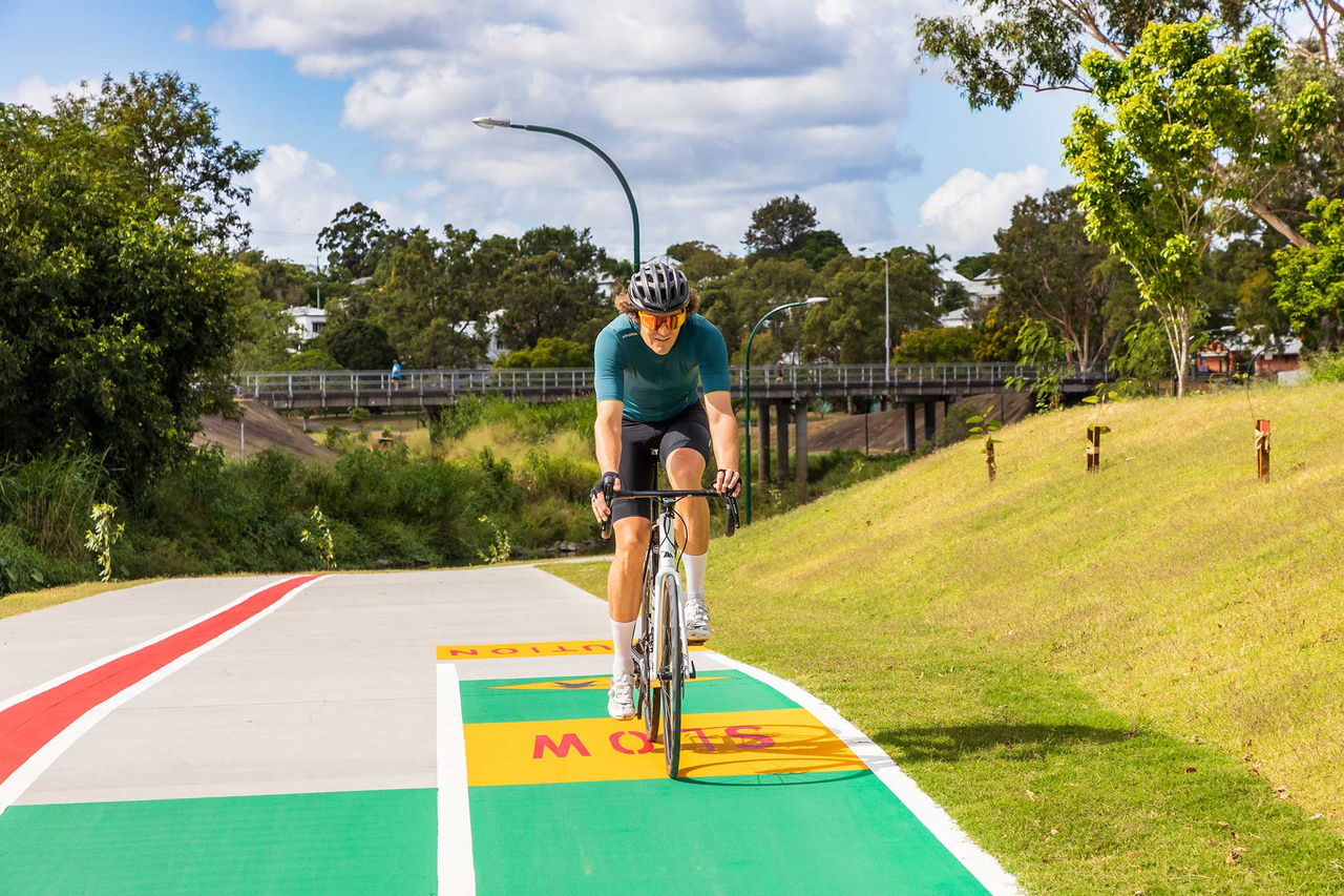 Man riding a bicycle along the Kedron Brook bikeway in Corbett Park.