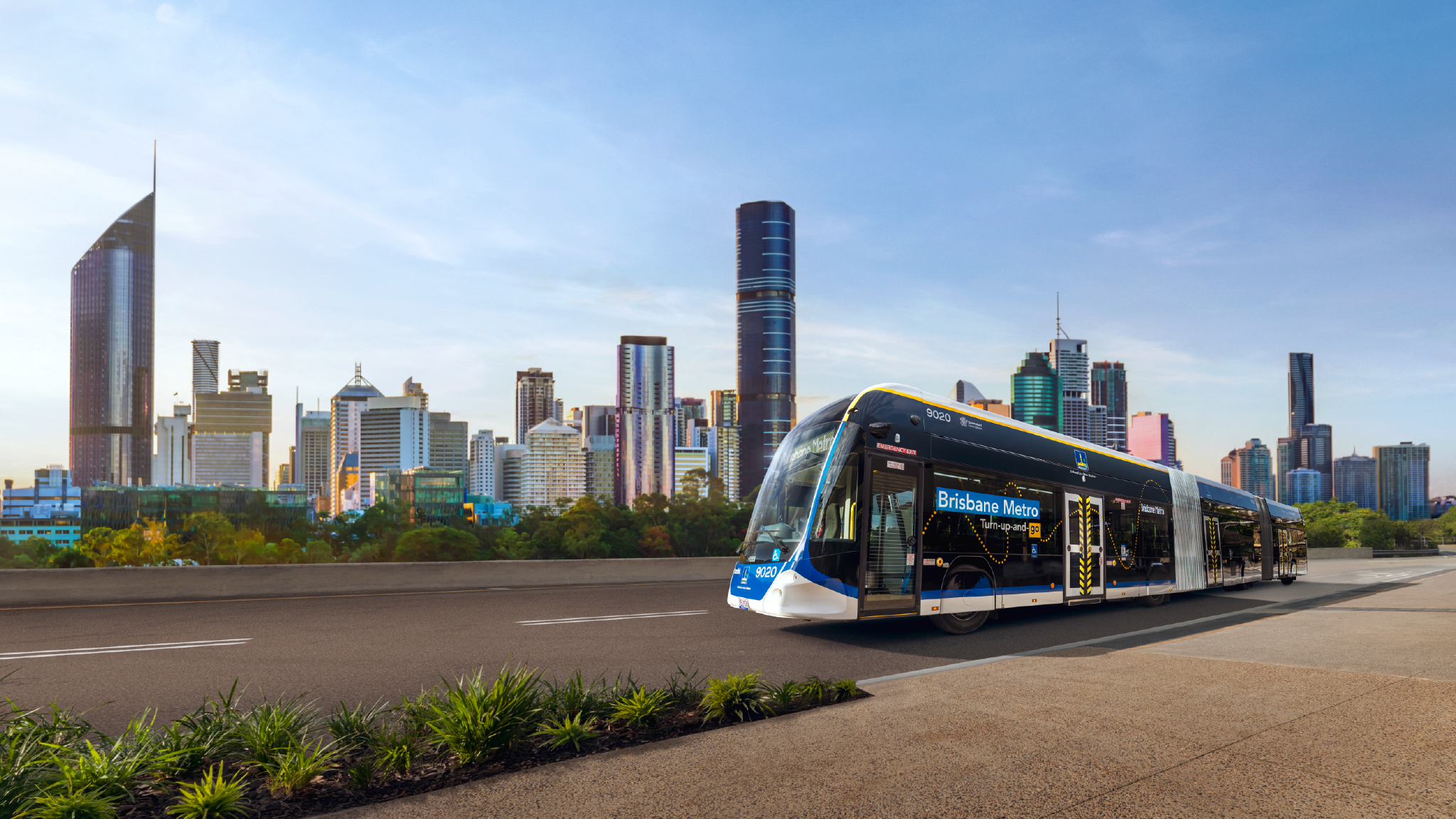 Brisbane Metro vehicle with '9020' on side and 'Brisbane Metro - Turn-up-and-go' on side. Brisbane CBD in background.