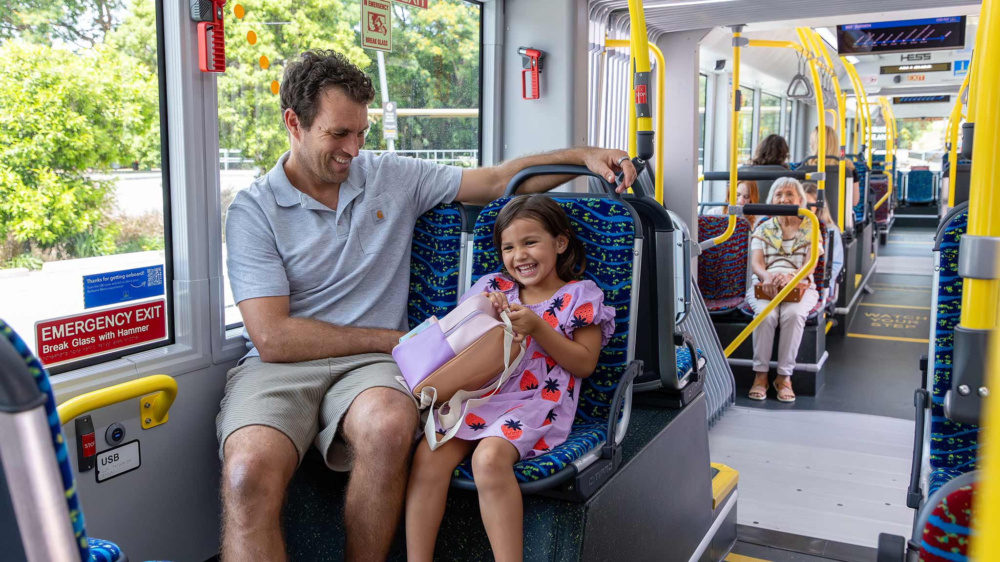 Father and daugher in foreground sitting in a Metro vehicle.