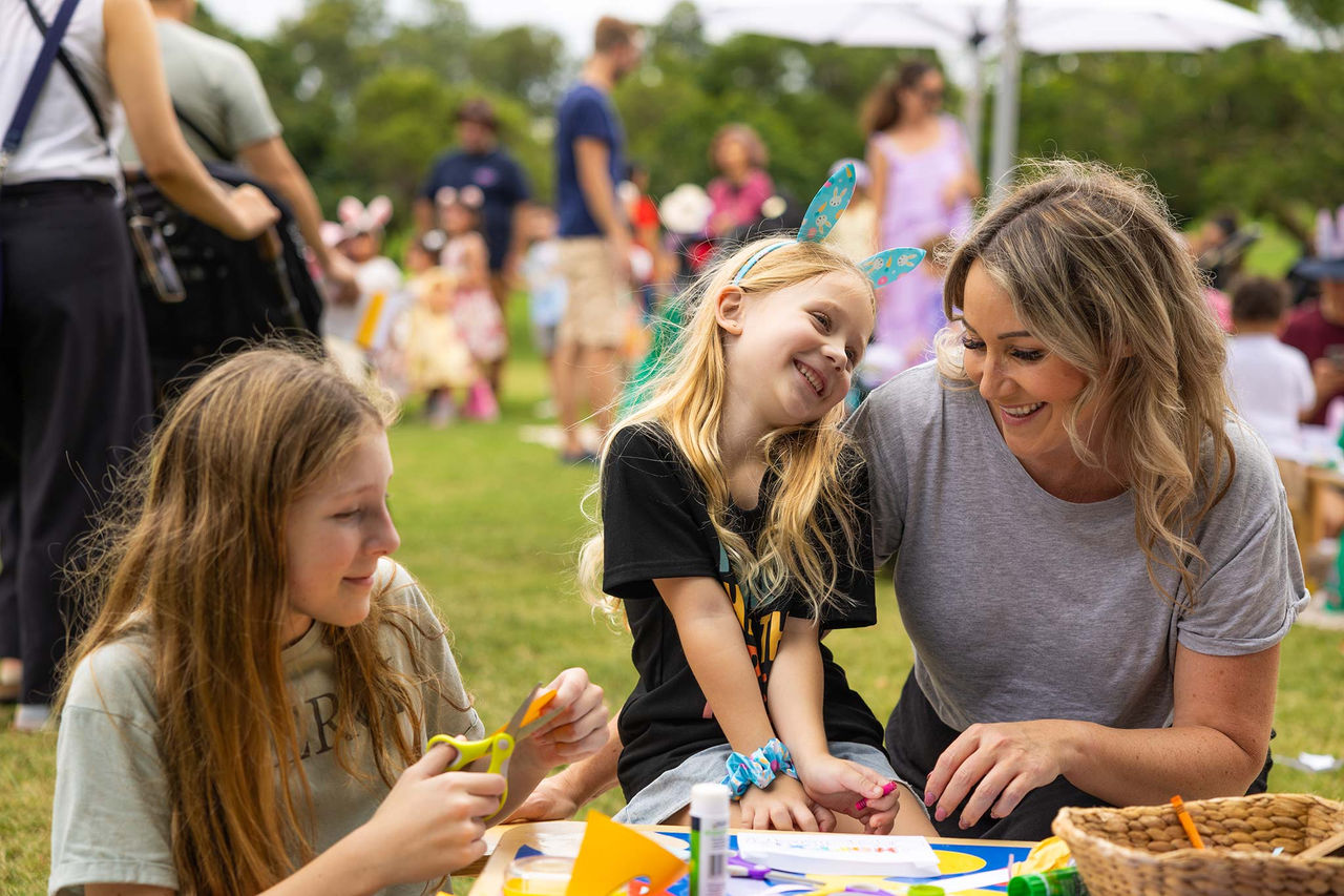 A Mum and her kids at a craft table at an Easter park event.