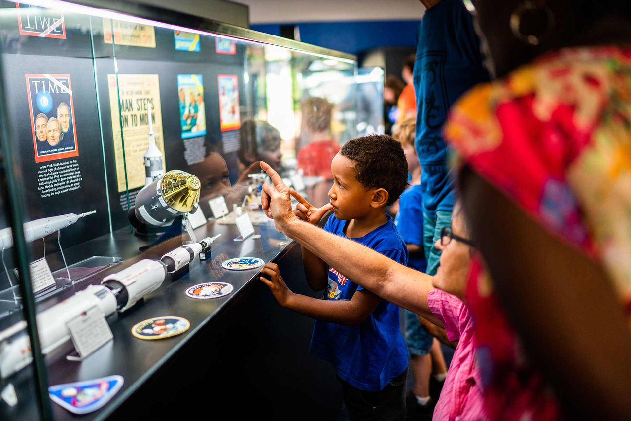 Young boy and adult looking at displays at Sir Thomas Brisbane Planetarium.
