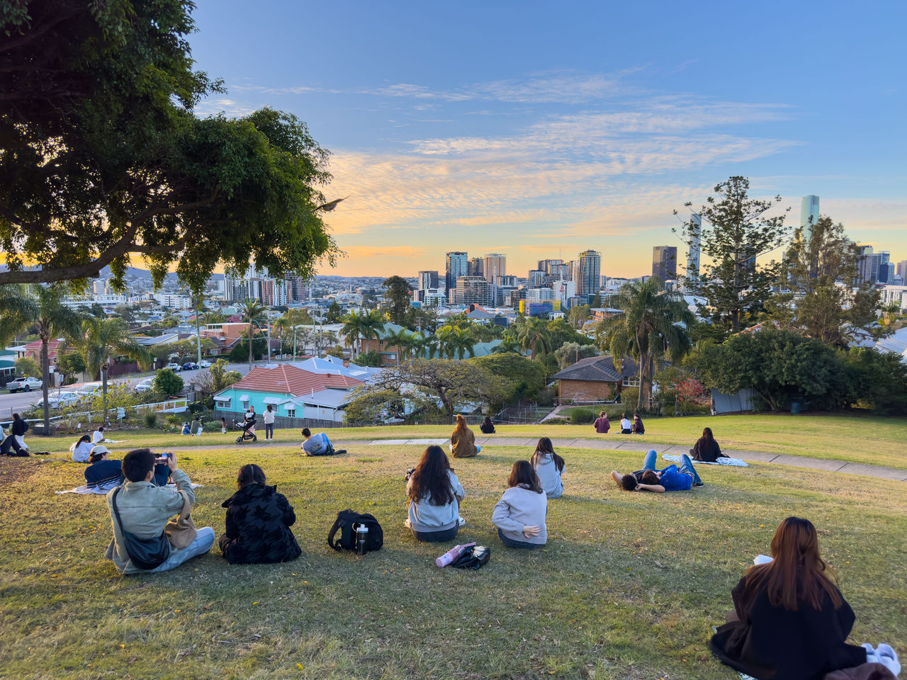 People sitting in Highgate Hill Park watching the sunset.