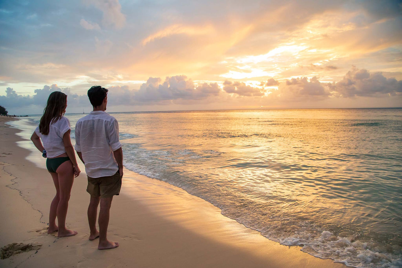 A couple standing on a beach on Moreton Island at sunset.