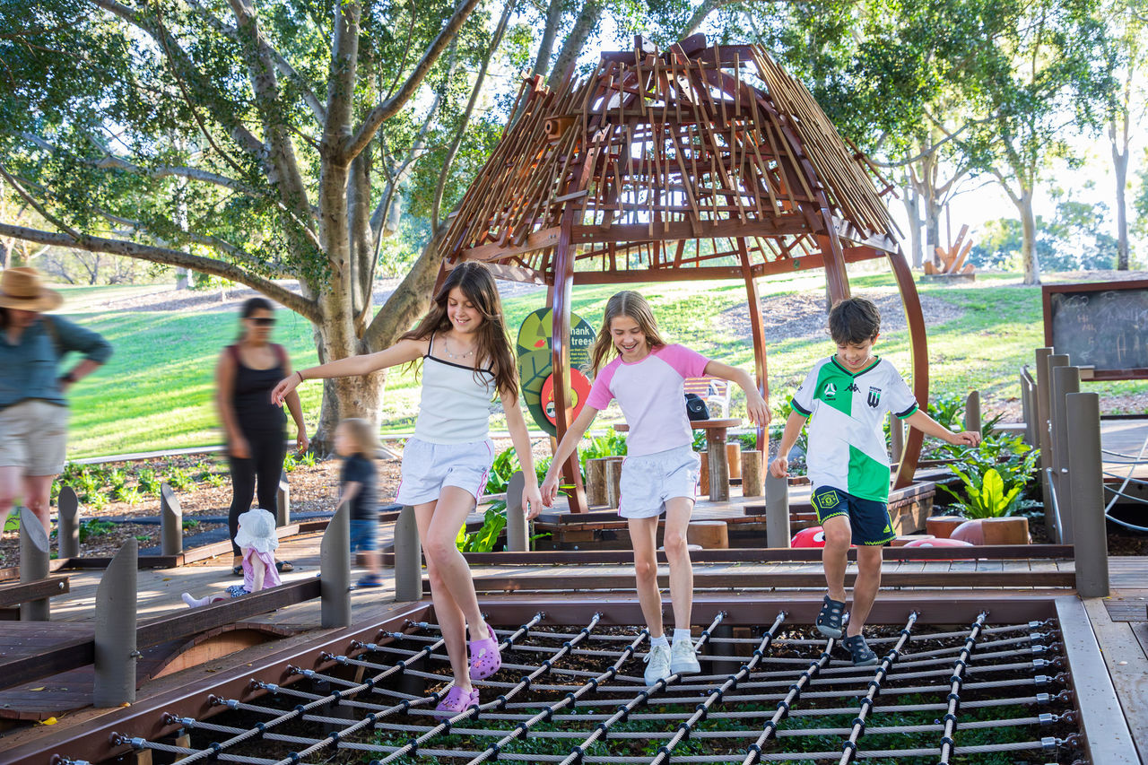 3 kids playing on playground equipment at Sherwood Arboretum.