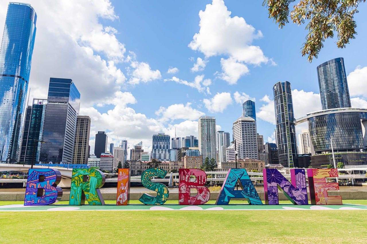 Brisbane sign at South Bank Parklands with Brisbane CBD in background.