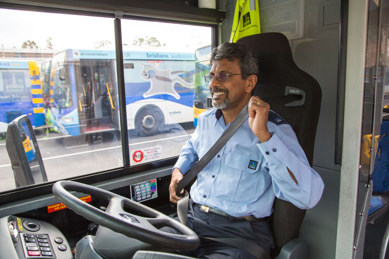 Council bus driver putting on a seatbelt in a bus