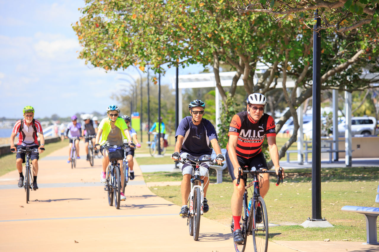 Seniors riding a Brisbane bikeway path as part of a GOLD event. 4 cyclists in primary focus.