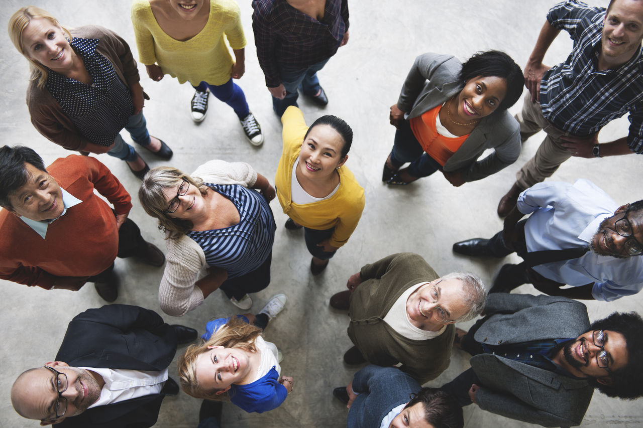 Group of adults from different multicultural backgrounds looking up at the camera.