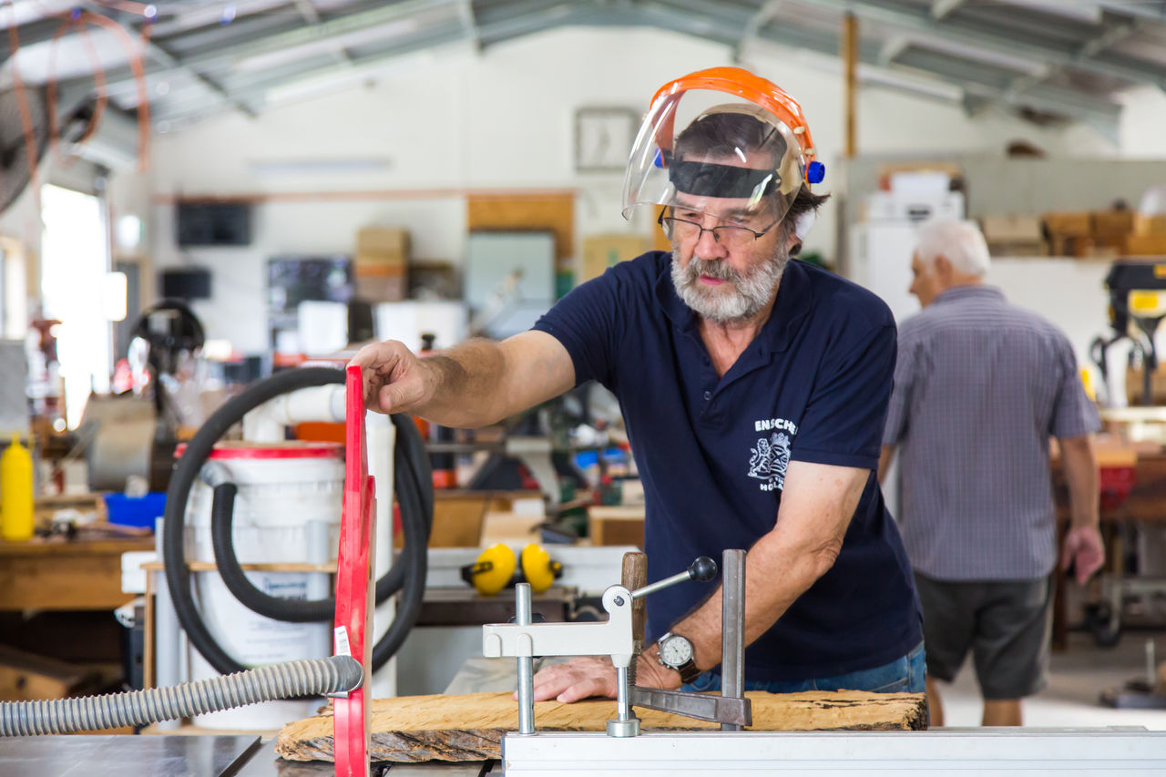 Senior man cutting wood at Wynnum Men's Shed.