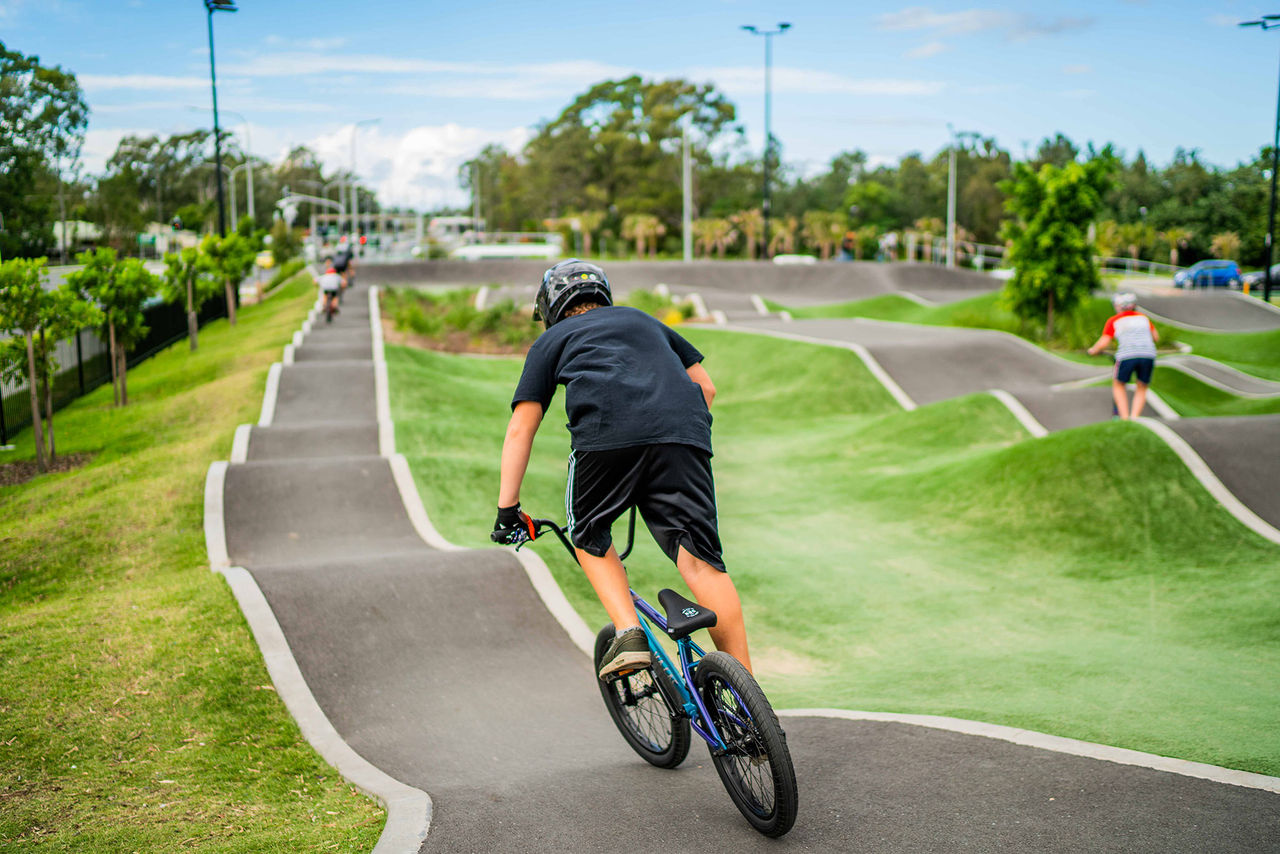 A teenage boy riding on a BMX bike at the BMX pump track facility at Bracken Ridge.