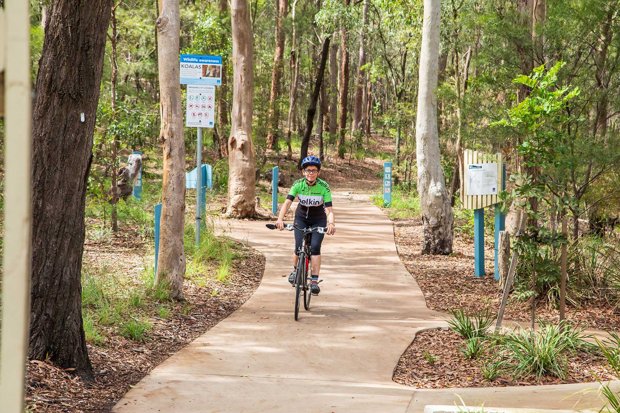 A person riding a bike along a pathway in a bushland area. 
