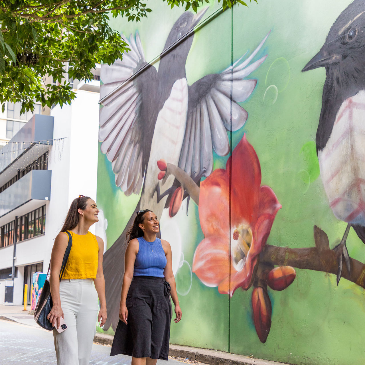 Two women walking down Fish Lane at South Brisbane looking at an artwork on a wall