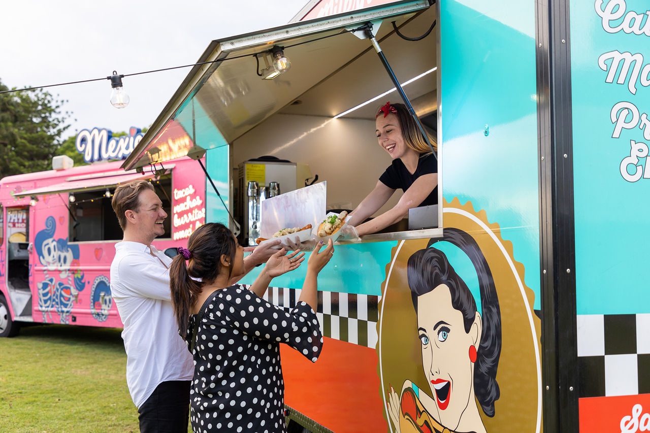 A man and woman collecting food from a food truck at an event at Victoria Park
