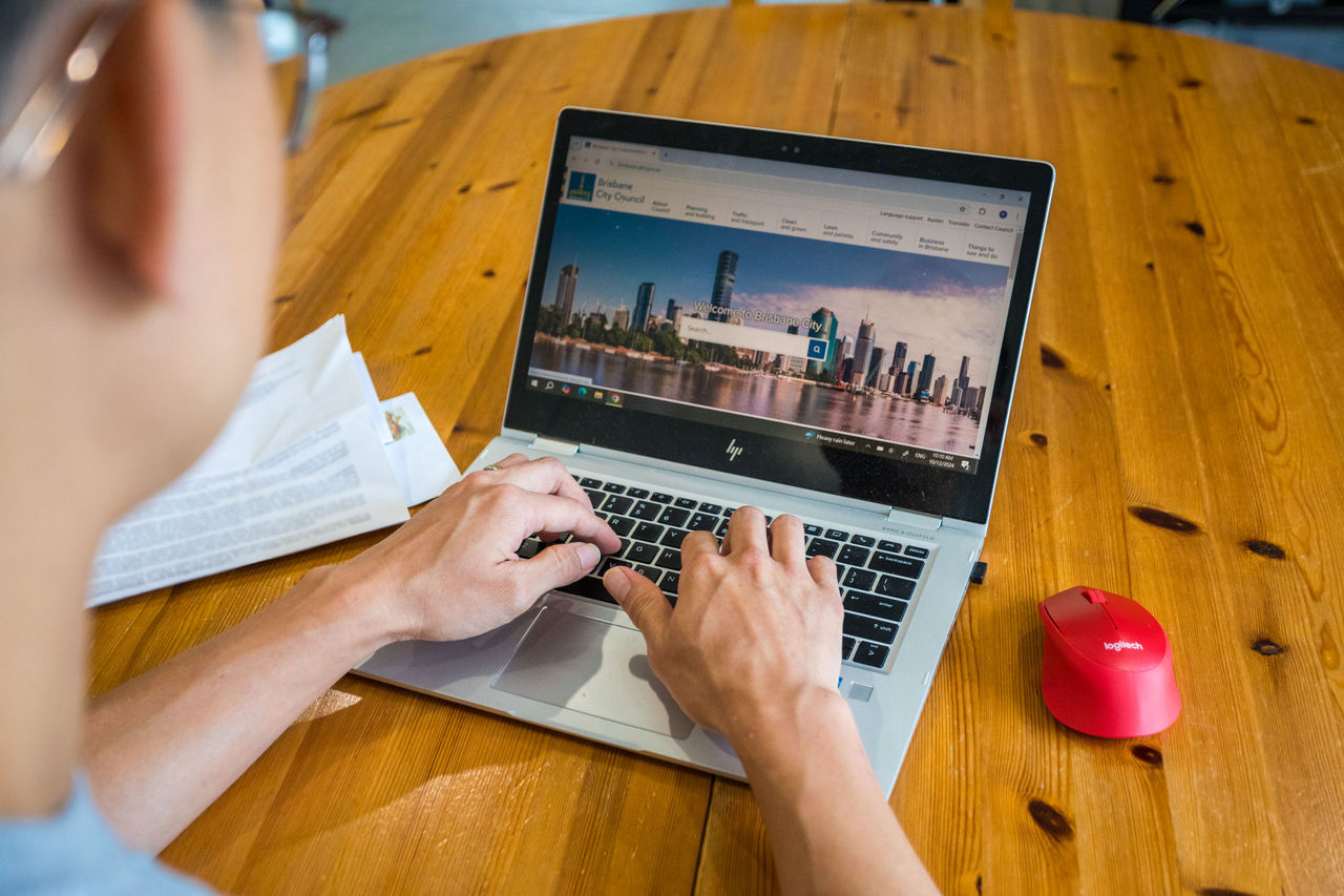 Man with glasses in business wear sitting at a desk using a laptop.