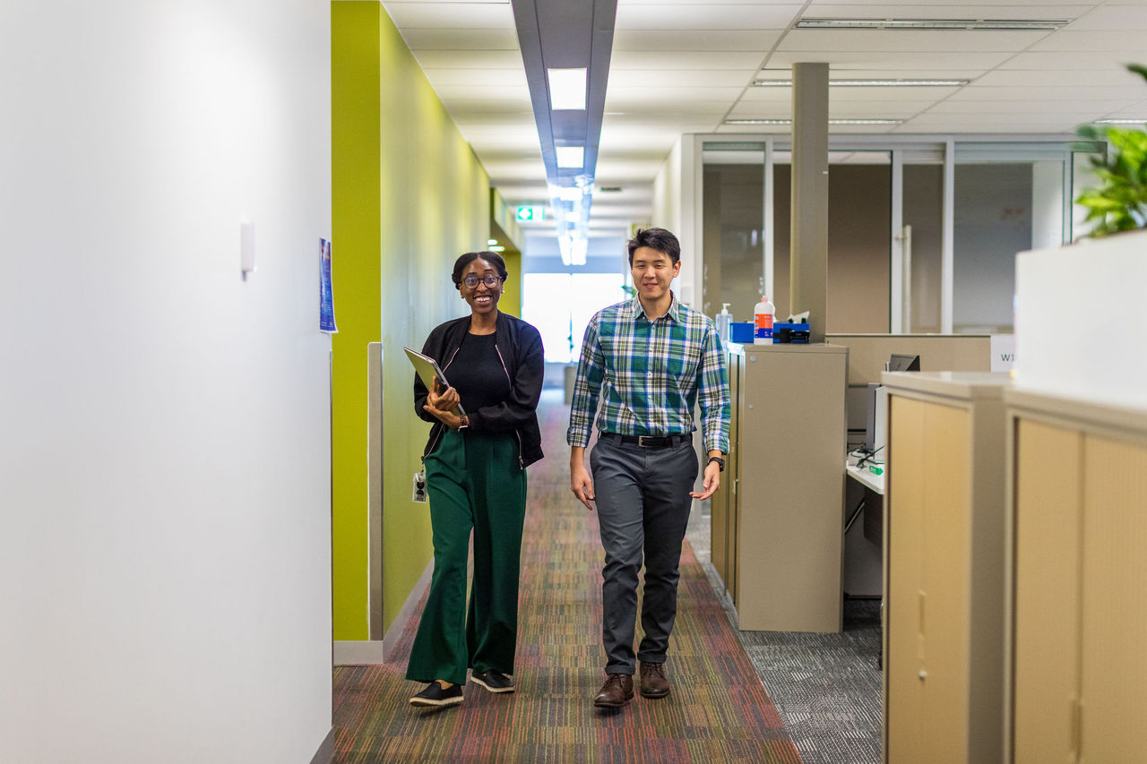Man and woman walking down a corridor in an office.