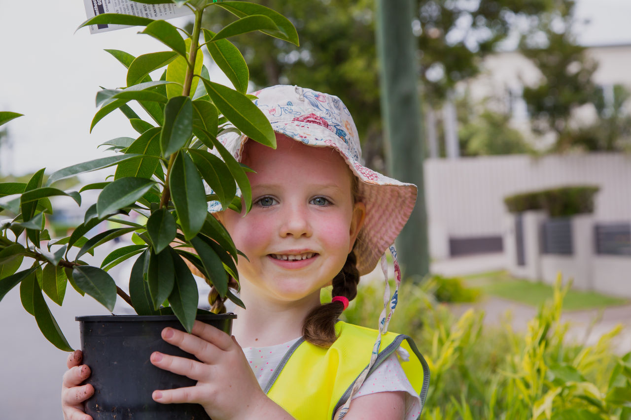 Young girl with a floppy hat and potted plant at a community street planting event in Highgate Hill.