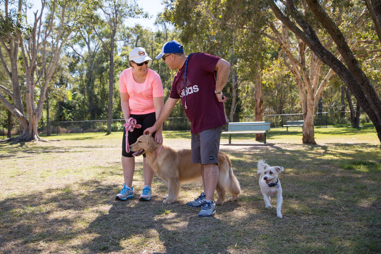 Couple in park with two different dog breeds. 