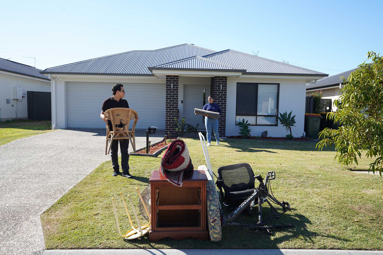 Two people putting items out on the footpath for kerbside collection.