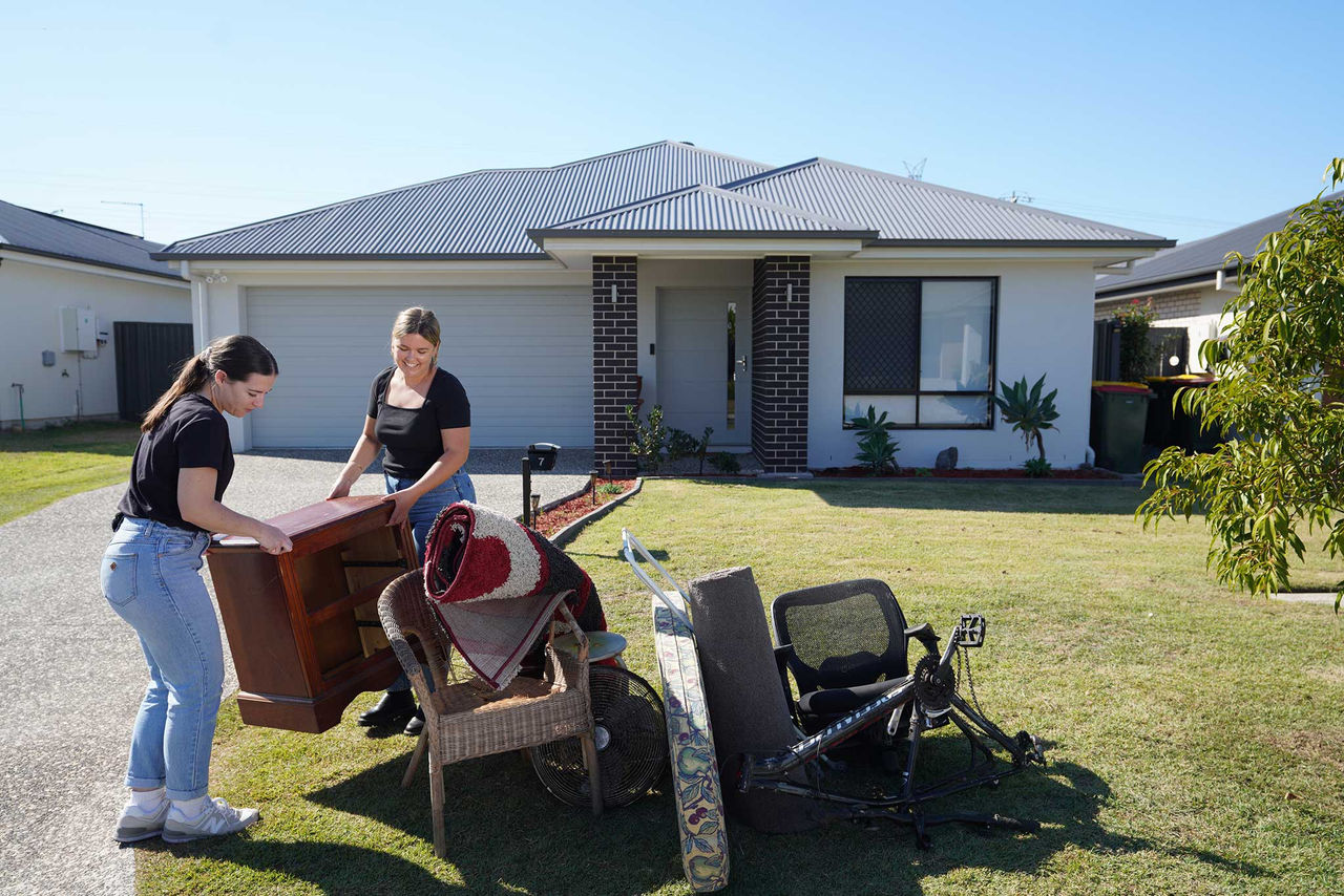Two women putting items out on the footpath for kerbside collection.