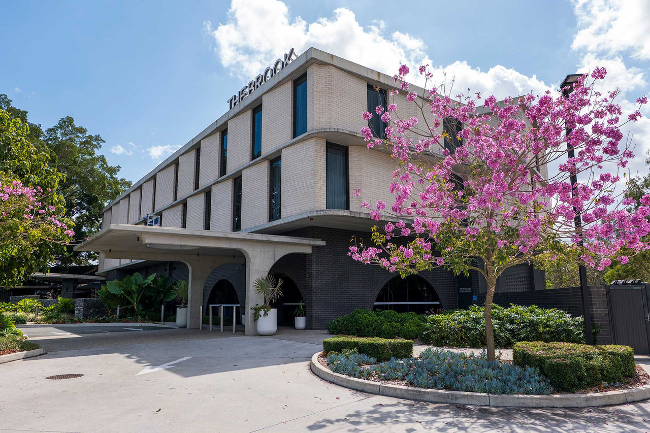 Front outside view of the Brook Hotel at Mitchelton with a tree with pink flowers beside.