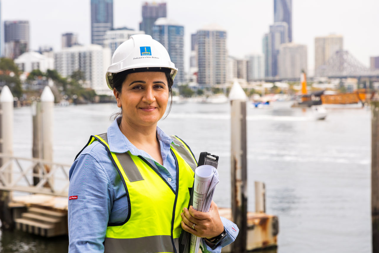 Female officer on a construction site with Kangaroo Point, Story Bridge and Brisbane CBD in background.