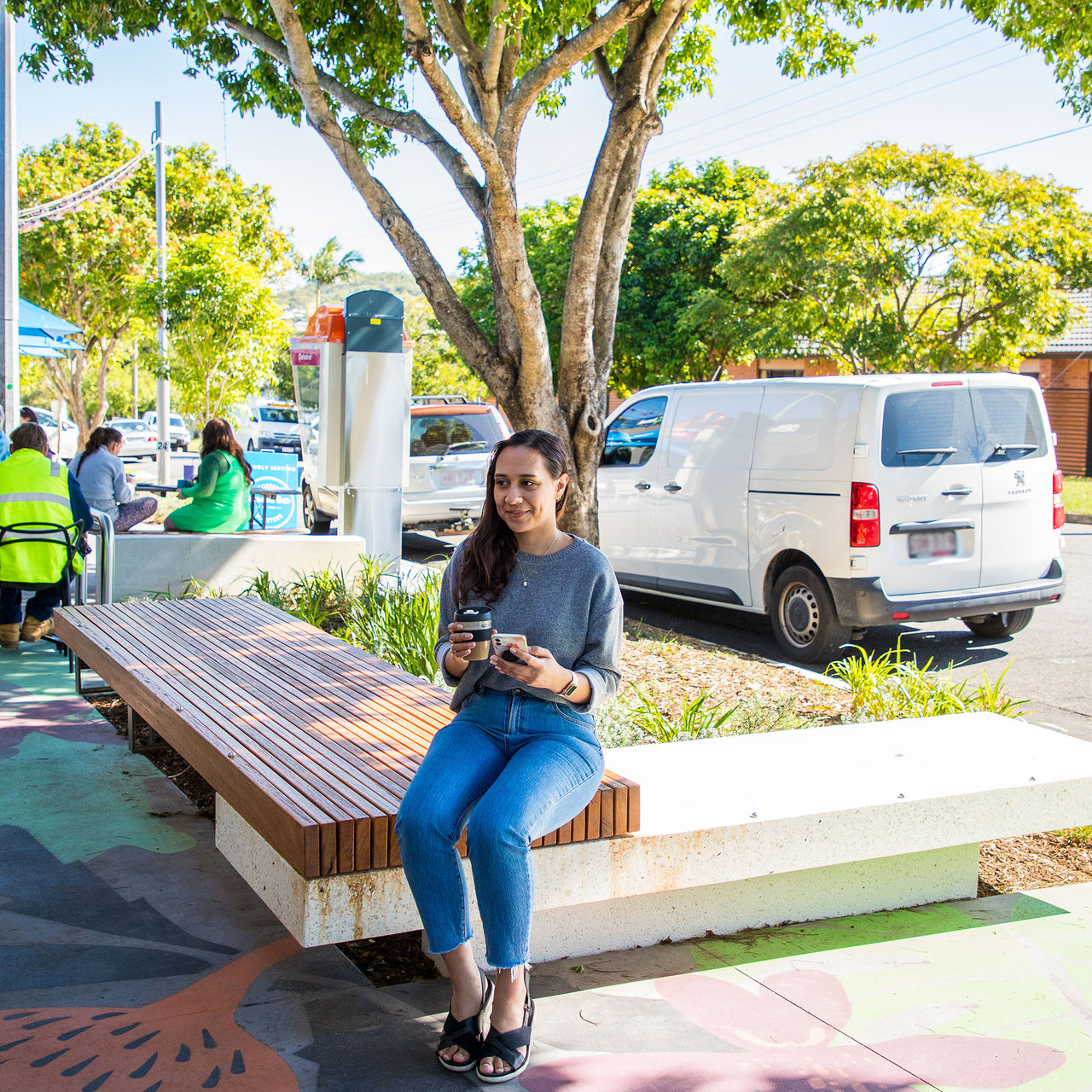 A woman sitting on a bench under a tree in the Lumley Street Village Precinct.