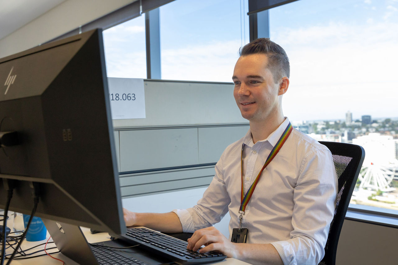 Man sitting at a work desk working on a desktop computer. 