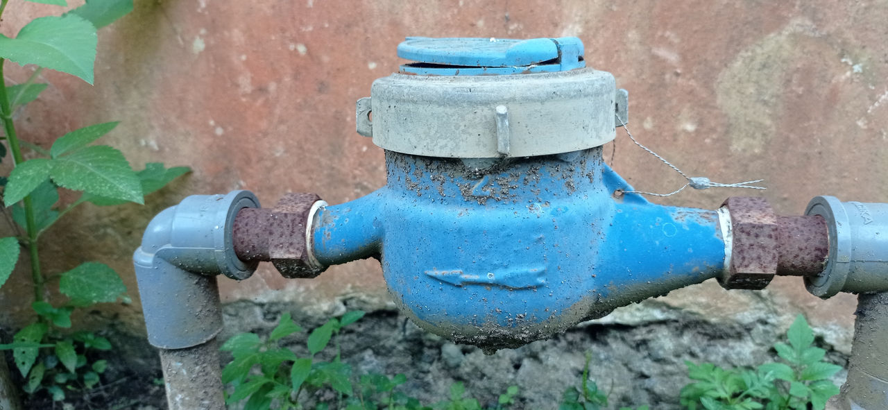 A blue-coloured backflow prevention device on a domestic property.. Some evidence of rust and weathering.