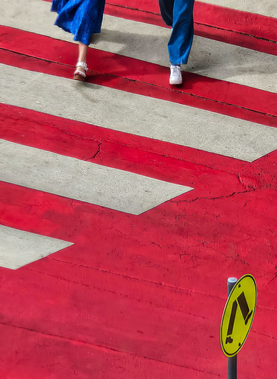 LMPA 2026 Peoples Choice Finalist - David Symons - Best foot forward. The feet of two people seen walking across a red and white pedestrian crossing.