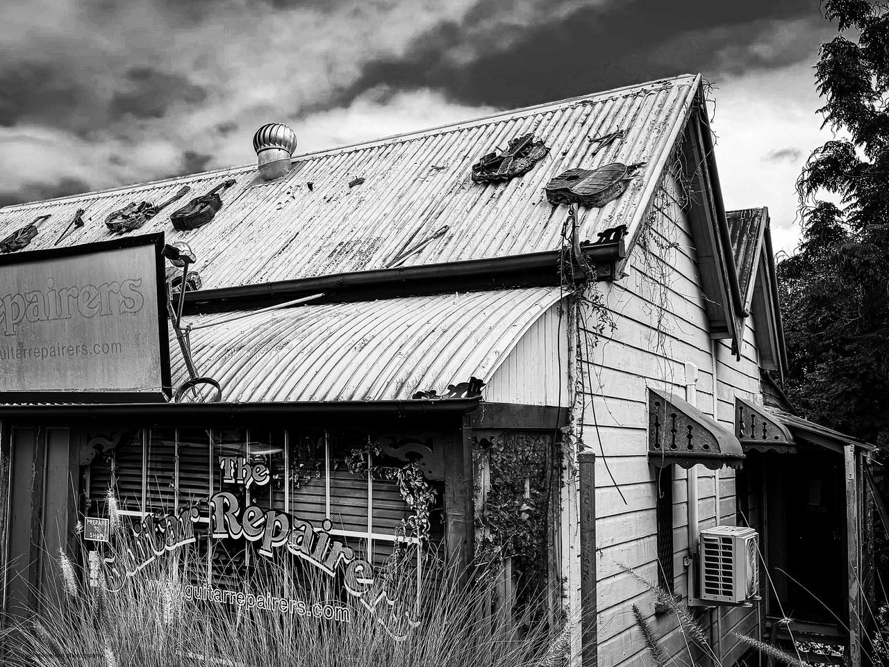 LMPA 2026 Peoples Choice Finalist - Paul Mikkelsen - Hidden in Plain View.  A black and white image of an old guitar repair shop with guitars on the roof.