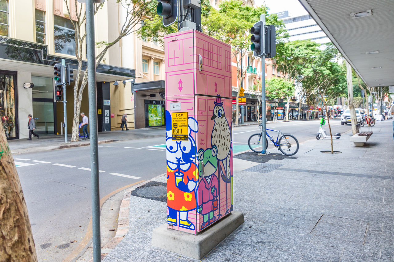 Colourful pink traffic signal box in Brisbane, painted with cartoon animals as part of the Artforce program.
