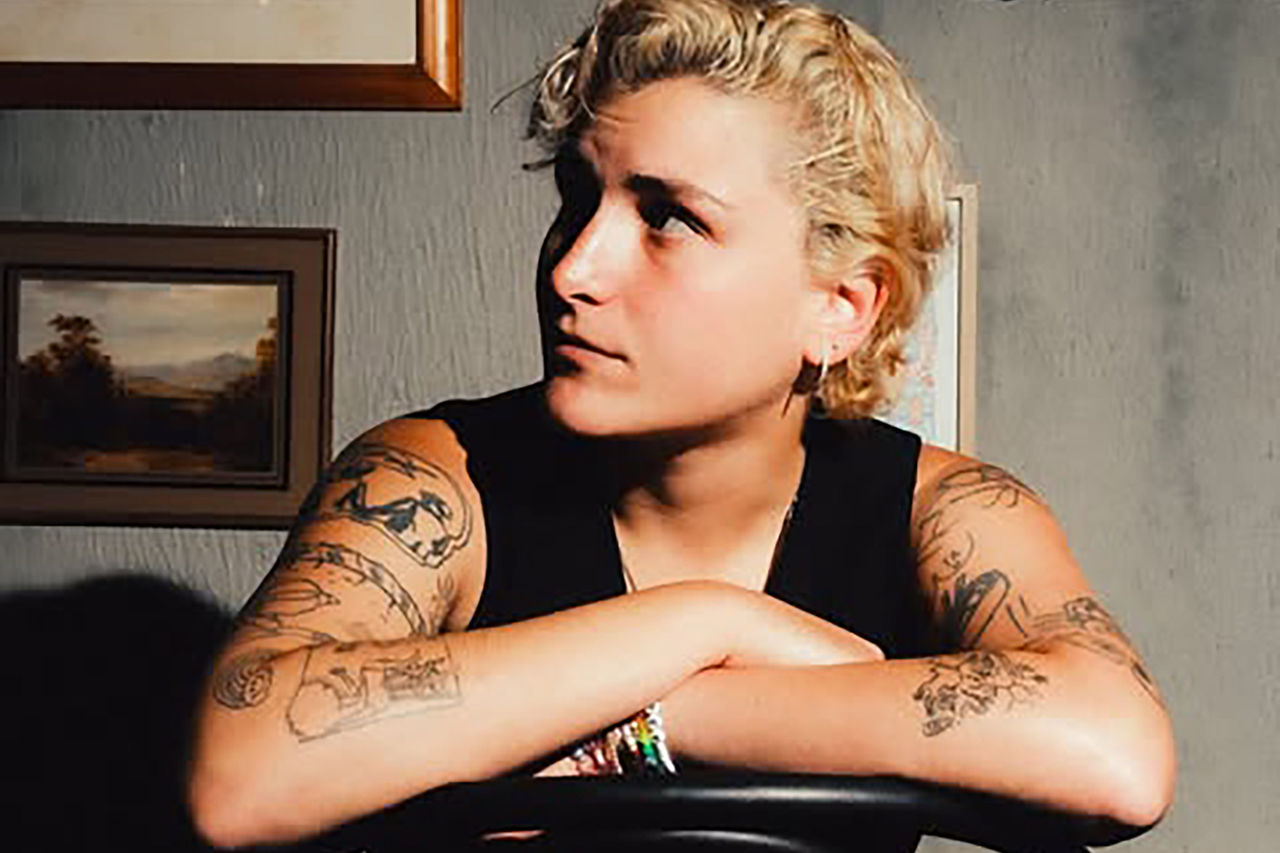 Portrait of Hope D sitting backwards in a chair with arms crossed.