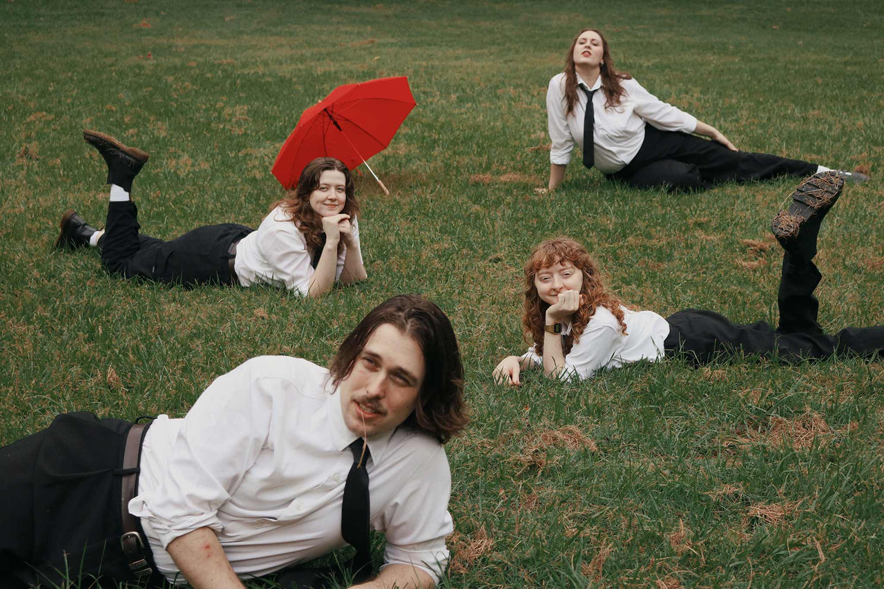 4 Red Hill band members lying on the grass.