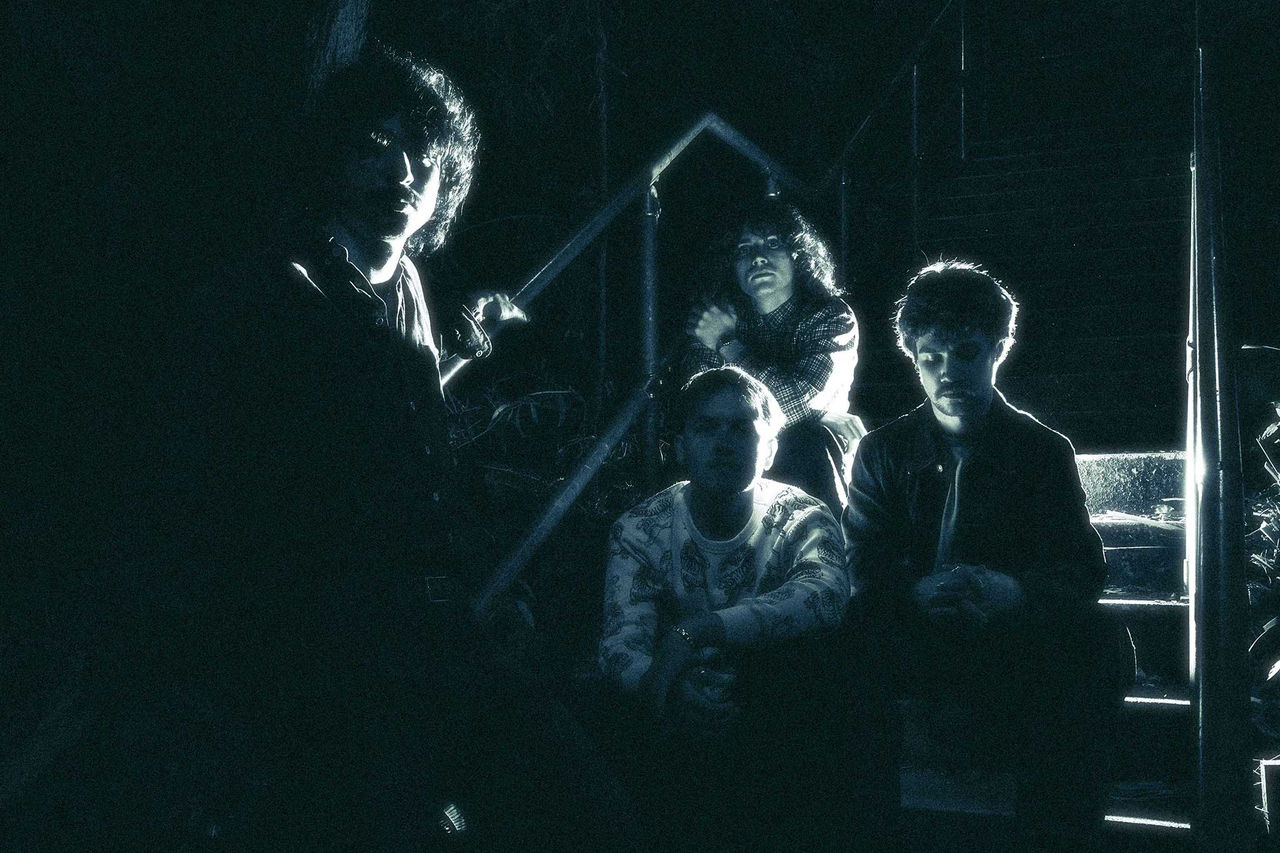 Vinted Vineer band members - finalists in The QUBE Effect 2026. Photographed at night on a staircase.