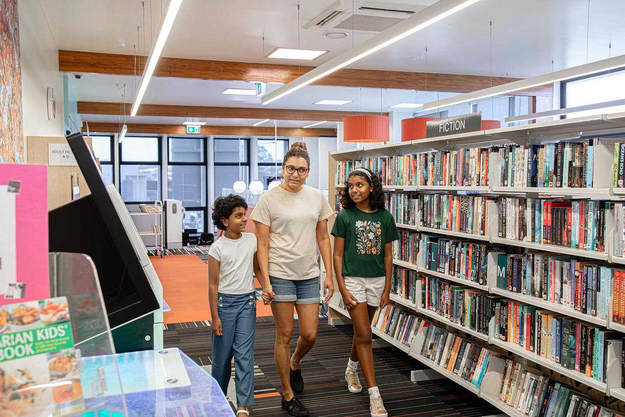 A woman with two girls walking through Nundah Library.