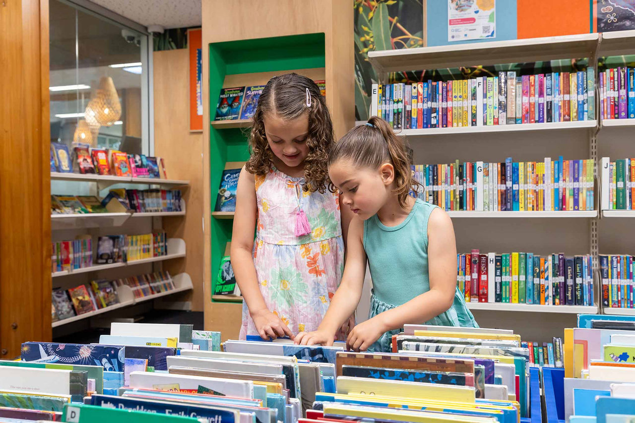 Two young girls looking at chidlrens' books at Ashgrove Library.