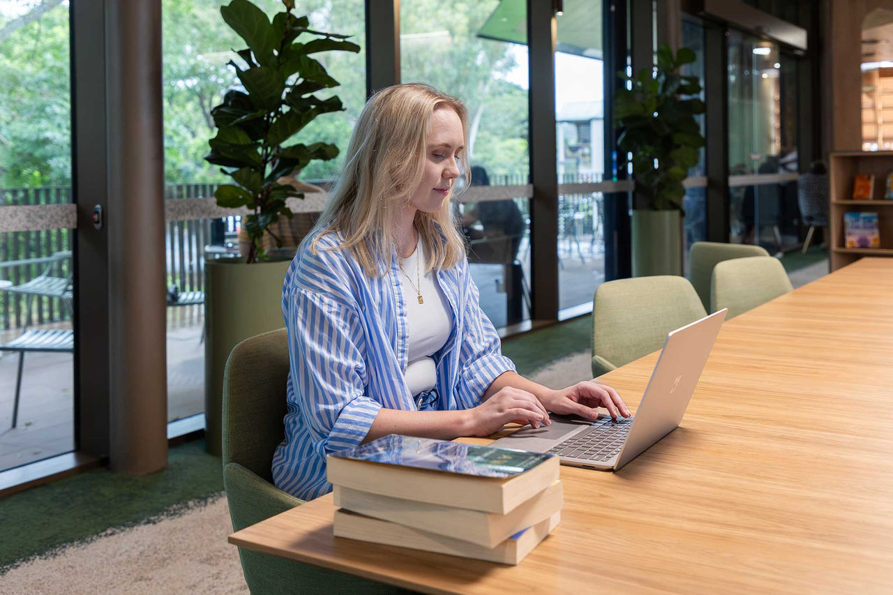 Woman using a computer on a large wooden desk at Eveton Park Library.