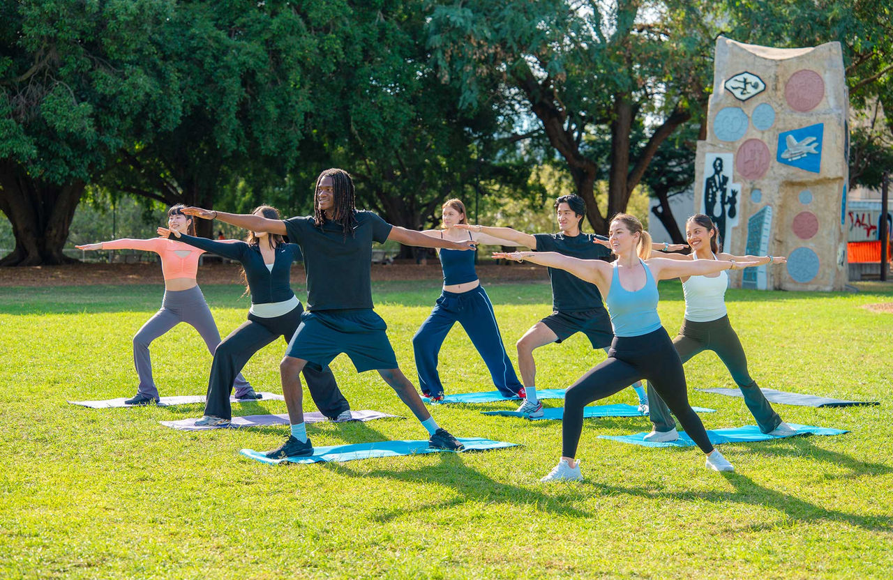 A group of people in yoga poses in a park.
